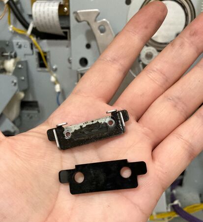 A worn shock absorber (in its holder) and a new one. Often by the time of printing failure, there is little or nothing left of the rubber absorber itself.