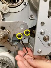 The two "fixing bolts" are marked, as well as the hex wrench angle for removing the left bolt.