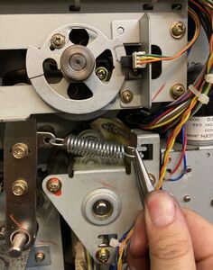 Detaching the right side of the timing spring with needlenose pliers (in this case it is hooked into the middle slot).